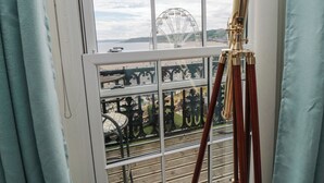Quarto com uma grande janela com vista para uma praia e uma roda gigante.