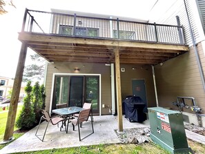 A covered patio with a table and chairs, a covered grill, and a door marked "Fire Room". - Luxury Creekside Condo , steps away from shopping & dining (Traverse City)