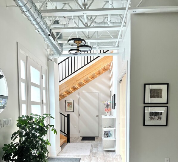 A modern interior with a staircase, white walls, and a ceiling with exposed beams and ductwork. - Luxury Creekside Condo , steps away from shopping & dining (Traverse City)