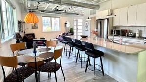 A spacious kitchen with a central island, modern appliances, and ample natural light from large windows. - Luxury Creekside Condo , steps away from shopping & dining (Traverse City)