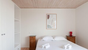 Un dormitorio con cama, dos mesitas de noche, un armario de madera y una obra de arte enmarcada en la pared.