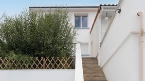 Un edificio blanco con una escalera de madera y un ventanal pequeño.