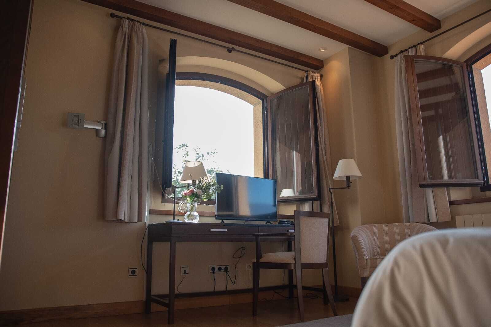 Una habitación de hotel con escritorio, silla, televisor, lámpara y cama.