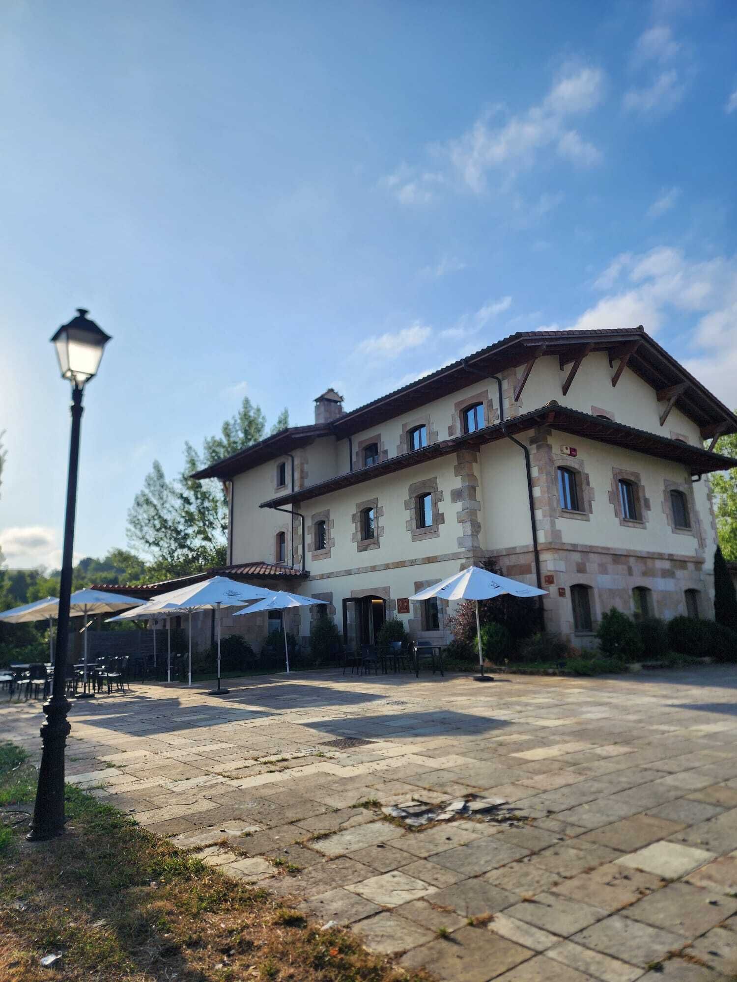 A large building with a courtyard, outdoor seating, and a street lamp.