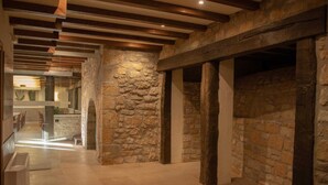 A corridor with stone walls and wooden beams, leading to a dining area with tables and chairs. - Arbizu (Arbizu)