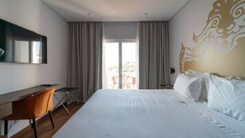 Una habitación de hotel con una cama grande, un escritorio y vistas al exterior a través de una puerta corredera.