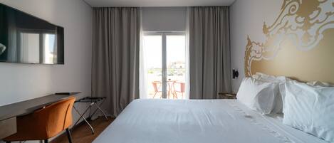 Una habitación de hotel con una cama grande, un escritorio y vistas al exterior a través de una puerta corredera.