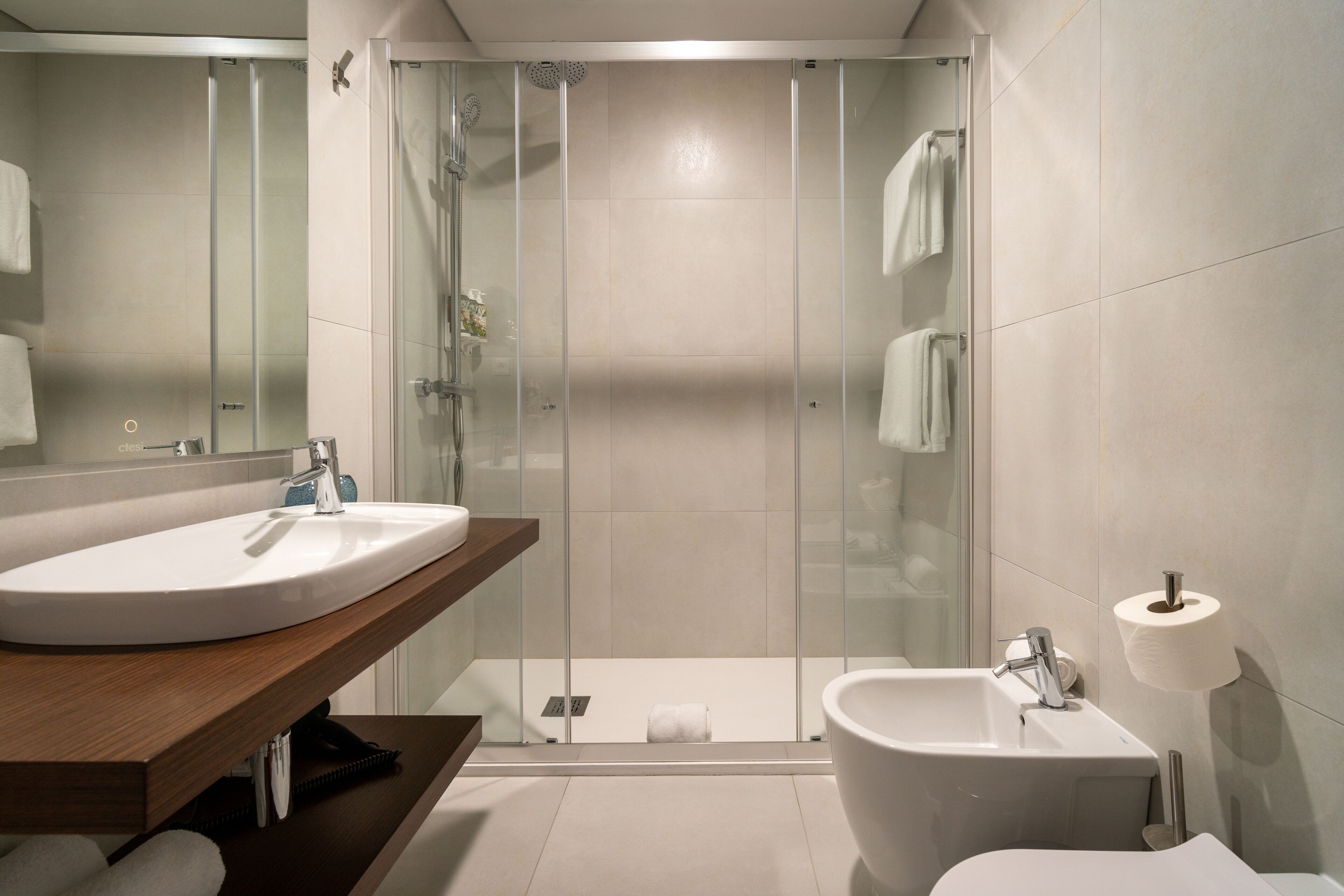 A modern bathroom with a glass-enclosed shower, a sink, and a bidet.