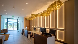 A modern reception area with a glass door entrance, a reception desk, and a seating area with chairs. - Palacio Santa Catarina Hotel (Angra do Heroismo)