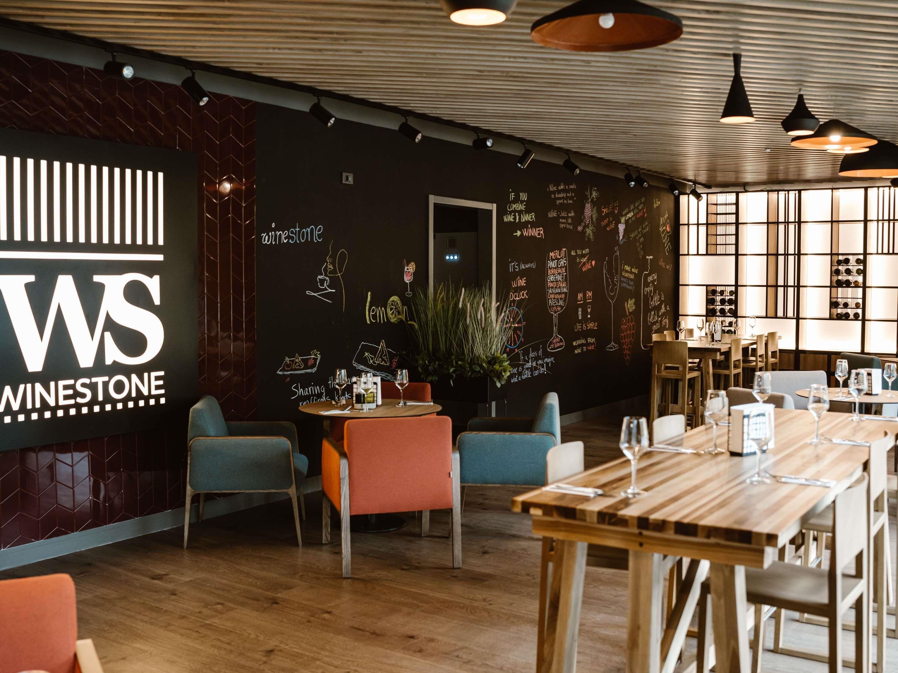L’intérieur d’un restaurant avec un menu écrit à la craie, des tables et des chaises en bois.