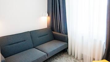 A small, modern room with a grey sofa, a patterned rug, and a yellow chair.