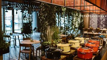 L'intérieur d'un restaurant, avec des tables, des chaises et des plantes suspendues.