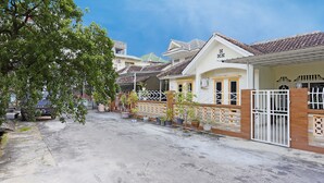 A residential street with houses featuring tiled roofs, potted plants, and a gated entrance. - Hotel O Wisma Pinggir (Tanjung Pinang)