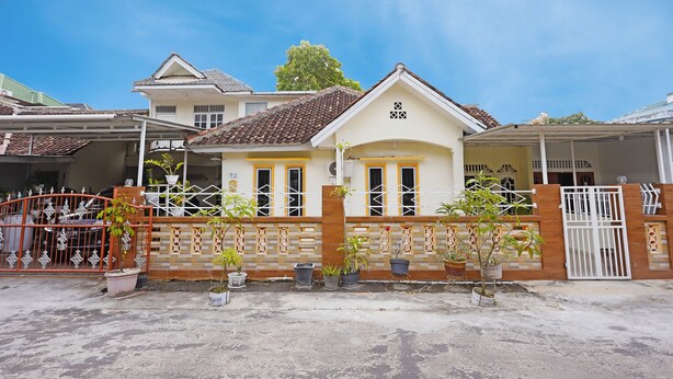 A two-story house with a tiled roof, a gated entrance, and potted plants. - Hotel O Wisma Pinggir (Tanjung Pinang)