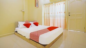 A neatly made bed with a patterned bedspread, a single red pillow, and a white pillow. There is a framed picture on the wall, a closed door, and an air conditioning unit on the ceiling. - Hotel O Wisma Pinggir (Tanjung Pinang)