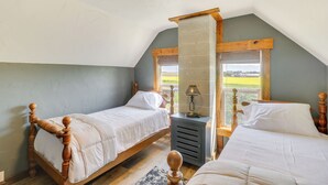 Een slaapkamer met twee houten bedden, een nachtkastje en een raam met uitzicht op de omgeving.