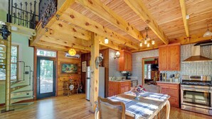 A spacious kitchen with wooden beams, a dining table with chairs, and a large oven. - Pet-Friendly Eureka Springs Rental w/ Private Deck (Eureka Springs)