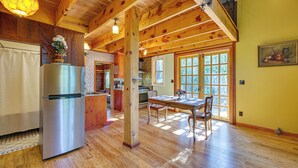 A spacious kitchen with wooden beams, a stainless steel refrigerator, and a dining area with a table and chairs. - Pet-Friendly Eureka Springs Rental w/ Private Deck (Eureka Springs)