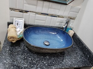 Une salle de bain avec un lavabo en céramique bleue, une serviette et un panneau indiquant où trouver les serviettes foncées destinées au maquillage.
