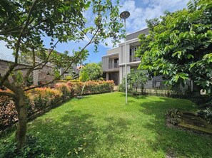 Une maison moderne à deux étages, dotée d’une pelouse et d’un jardin bien entretenus.