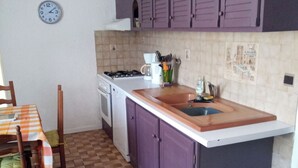 A kitchen with purple cabinets, a tiled floor, a sink, and a stove.