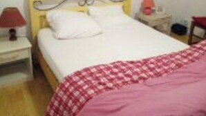 A bedroom with a bed, a nightstand, a lamp, and a wall with a painting.