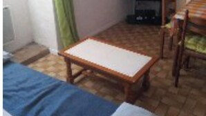 A small, cozy room with a bed, a table, and a TV.