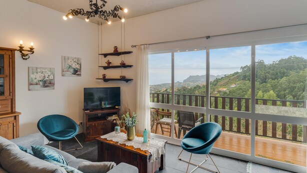 Un salón amplio con un gran ventanal que ofrece una vista panorámica de una zona boscosa.