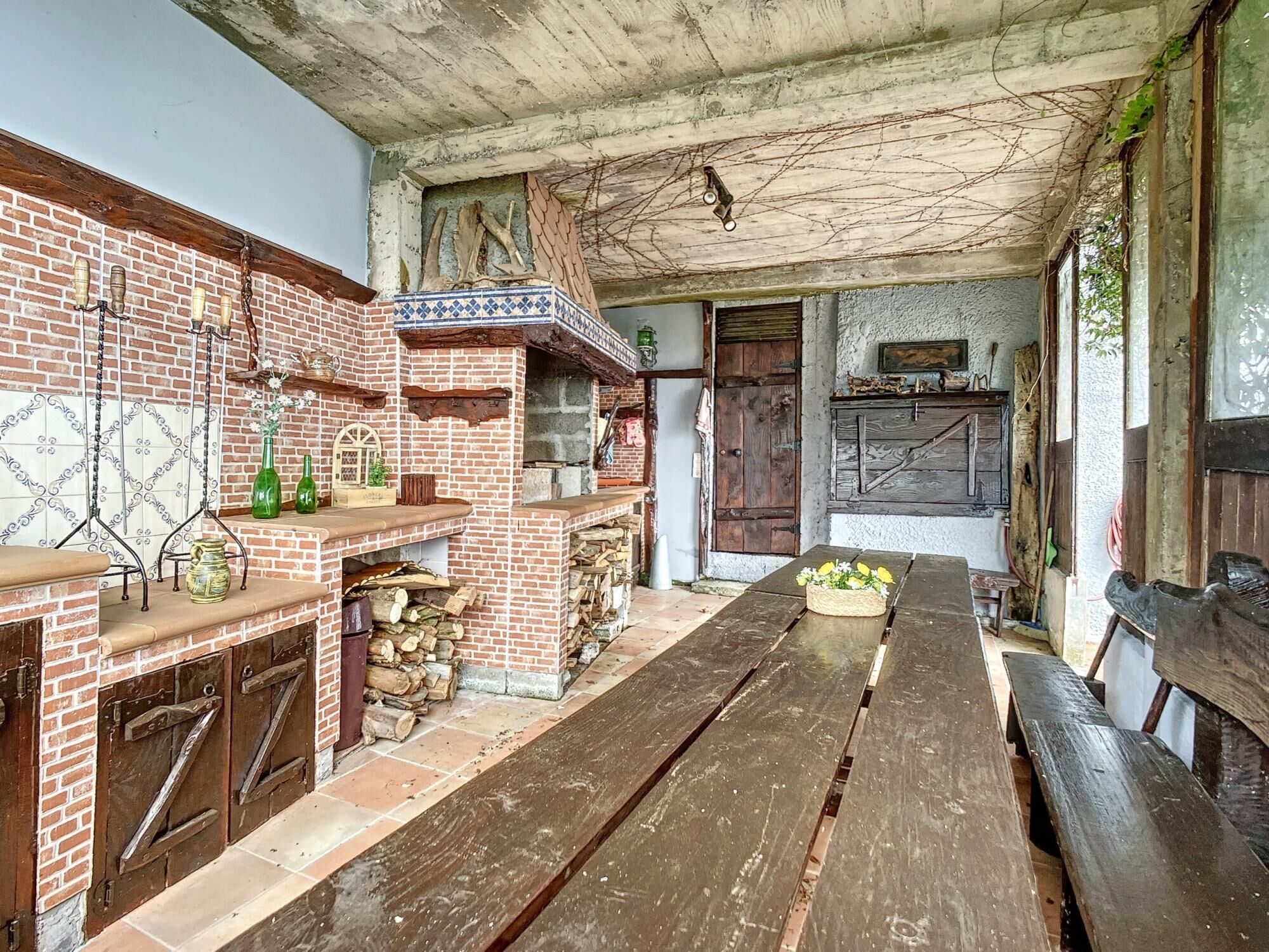 A rustic kitchen with a brick wall, wooden bench, and a tiled backsplash.