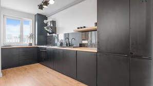 Una cocina moderna con armarios negros, encimera de madera y horno integrado.