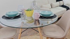 Una sala de estar moderna con una mesa redonda de vidrio, dos sillones, un sofá y un reloj de pared.