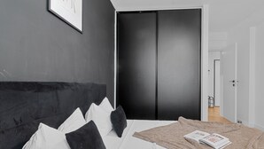 Un dormitorio con una cama grande, paredes oscuras y un armario negro.