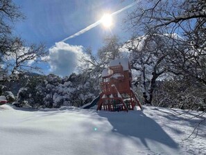 Eine Holzhütte in verschneiter Landschaft unter blauem Himmel.