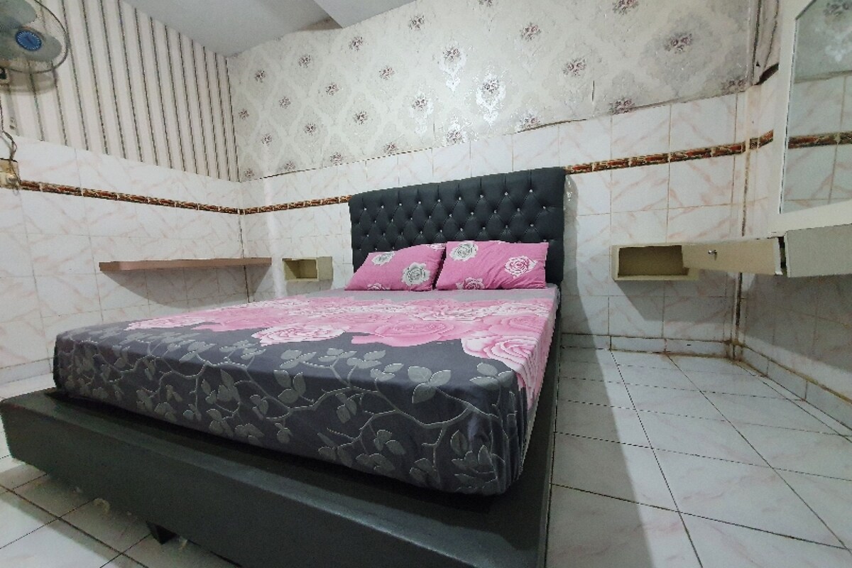 Une chambre à coucher avec un lit, une table de chevet et une étagère fixée au mur.