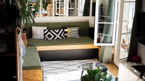 Ein gemütliches, helles Zimmer mit Bett, Sitzgelegenheit und Esstisch.
