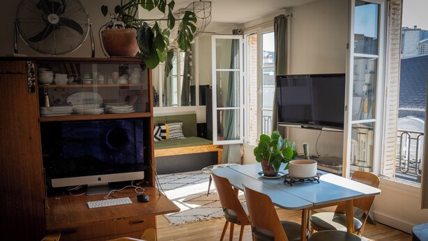 Ein gemütliches Wohnzimmer mit einem Holztisch, einem großen Flachbildfernseher und einer komfortablen Sitzecke mit Sofa und Esstisch.