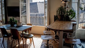 Eine moderne Küche mit großem Fenster, Holzboden und einem Essbereich mit Stühlen und Barhocker.