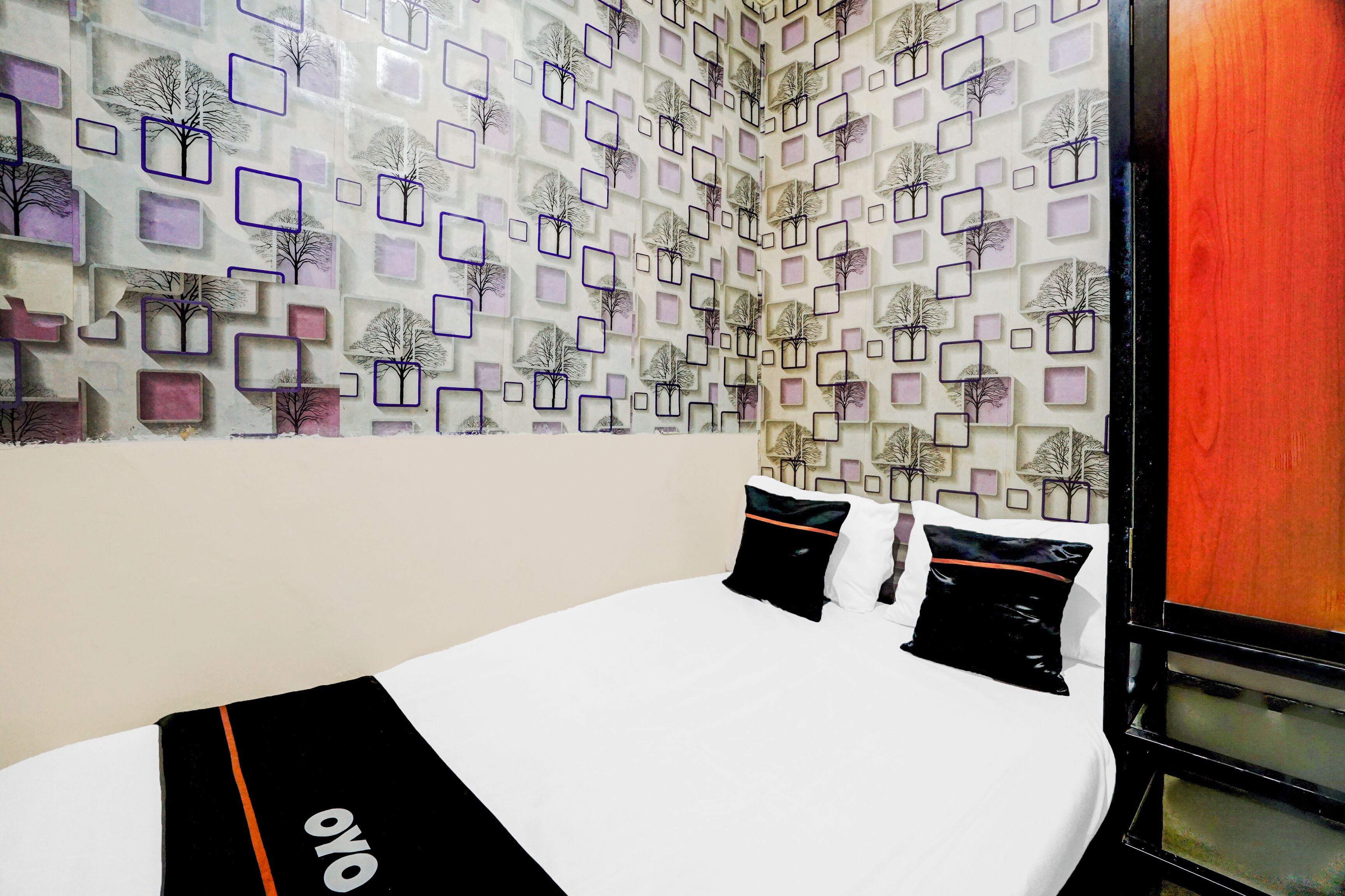 Una camera d'albergo con un letto, biancheria da letto bianca e una parete con motivo geometrico.