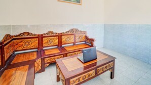 A traditional wooden sofa set with a laptop on a matching table. - Hotel O Surabaya near Universitas Airlangga formerly Kertajaya Residence Surabaya (Surabaya)
