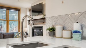 A modern kitchen with a large sink, a built-in oven, and a herringbone-patterned backsplash.