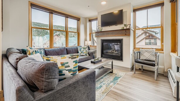 A modern living room with a fireplace, large windows, and a cozy seating area.
