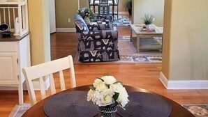 A dining area with a round table, chairs, and a vase with flowers. - Savannah Inn Anhors Away (Lewes)