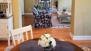 A dining area with a round table, chairs, and a vase of flowers. - Savannah Inn Bay Breeze (Lewes)
