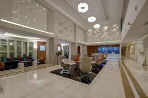 A spacious lobby with a reception desk, seating area, and a large window.