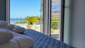 A balcony with a view of the sea, a pool, and a palm tree. - Villa Ballerina Bianca with private pool (Scopello)