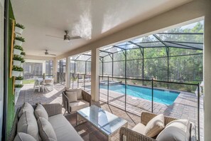 A spacious indoor area with a glass-enclosed pool, comfortable seating, and a view of the outdoors. - Storey Lake 9 BR Themed Games Room (Kissimmee)