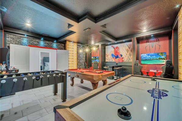A modern indoor recreational area with a foosball table, pool table, and a large TV screen. - Storey Lake 9 BR Themed Games Room (Kissimmee)