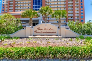Schild für 'San Carlos Condominiums', mit Blick auf ein mehrgeschossiges Gebäude im Hintergrund.