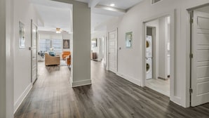A spacious hallway with hardwood flooring, white walls, and multiple doors leading to different rooms. - Luxury 4BD Condo Near French Quarter – Prime Location! (New Orleans)