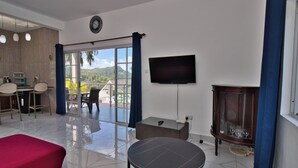Een hotelkamer met een bed, een zithoek met stoelen en een tafel, een televisie en uitzicht op de omgeving.